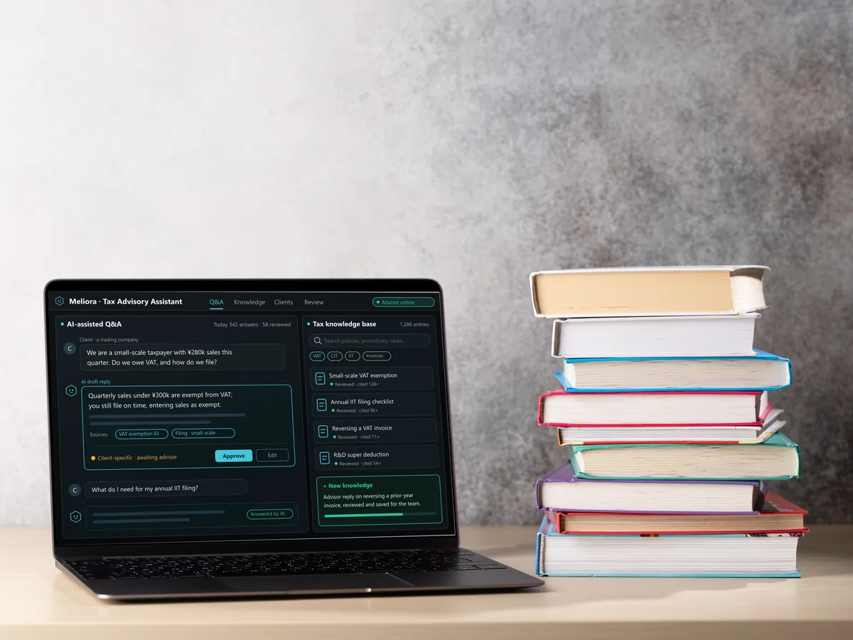 A laptop beside a stack of books showing AI-assisted Q&A and the tax knowledge base